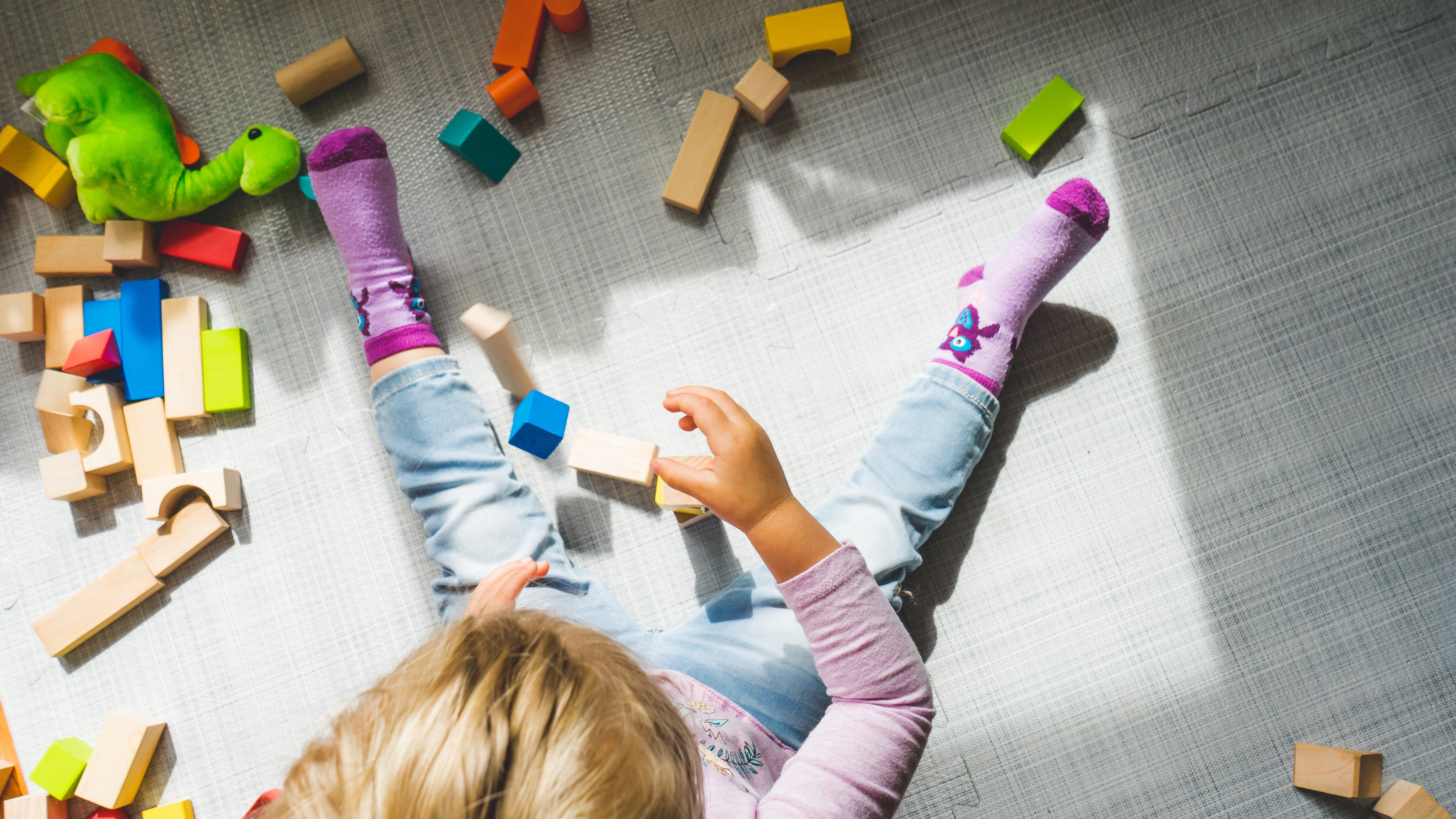 Child on floor playing with colorful blocks